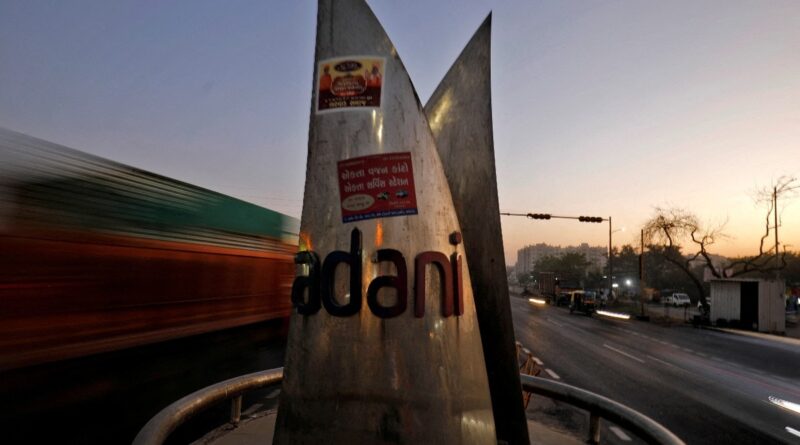 Traffic moves past the logo of the Adani Group installed at a roundabout on the ring road in Ahmedabad, India